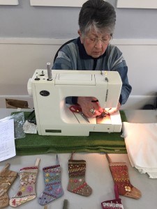Kay demonstrating at her machine behind some of her own creations.